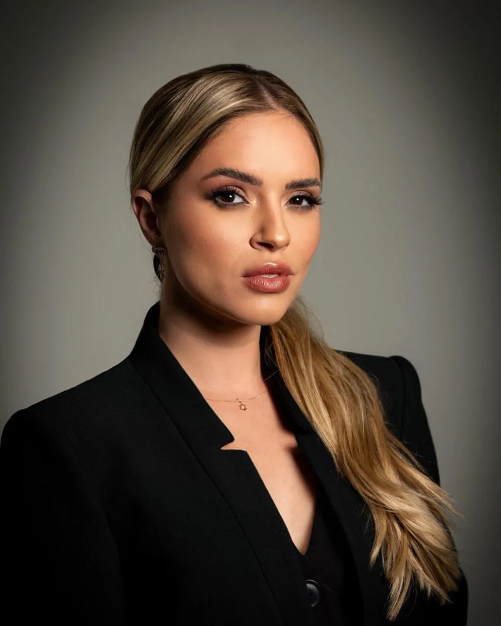 Dra. Fernanda Nogueira Portes, de blazer preto, em fundo cinza