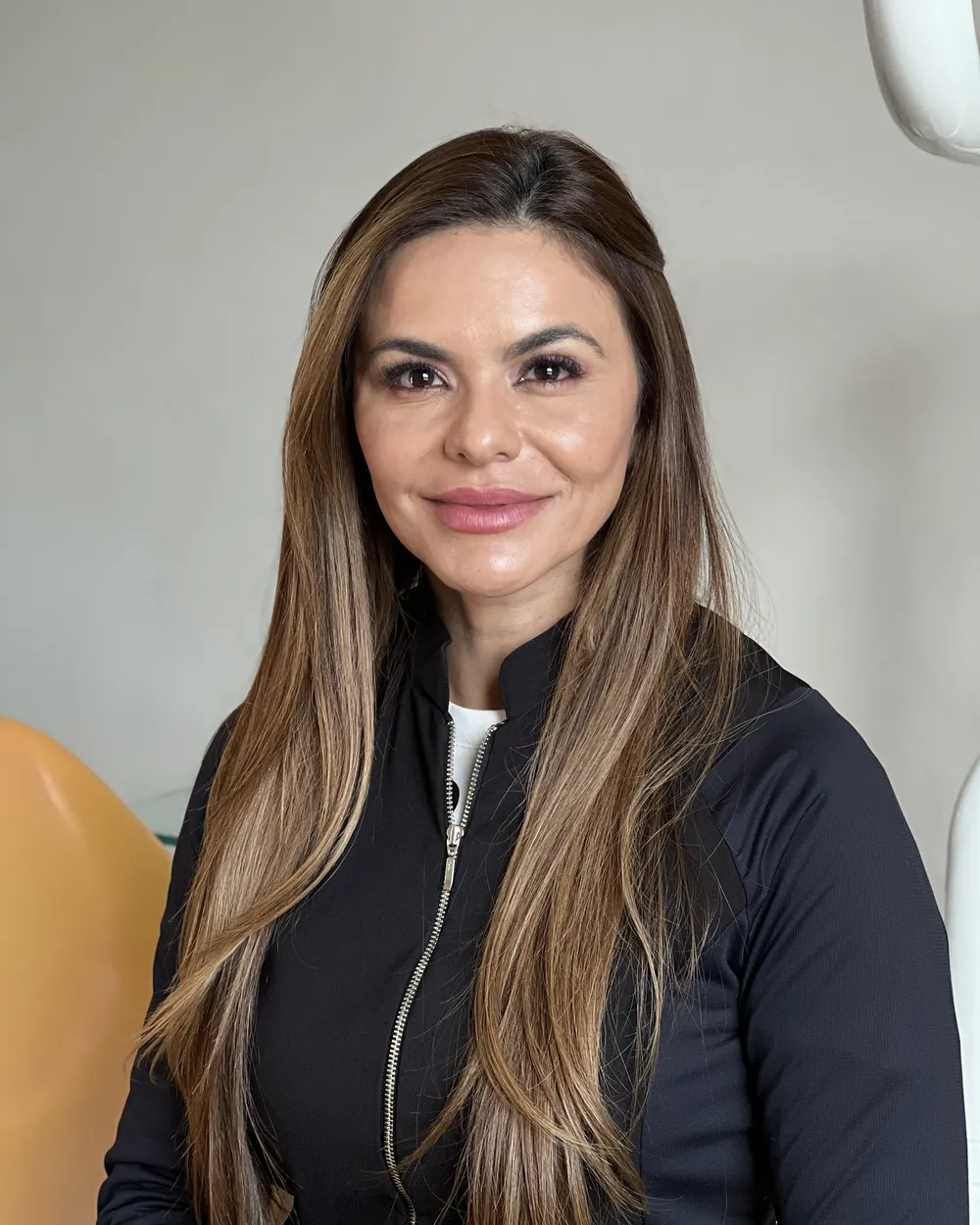 Dra. Lídia Scatulino, especialista em Harmonização Orofacial, de jaqueta preta no consultório da OrthoVip