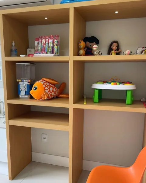 Estante de madeira com brinquedos e peixe de pelúcia no consultório infantil